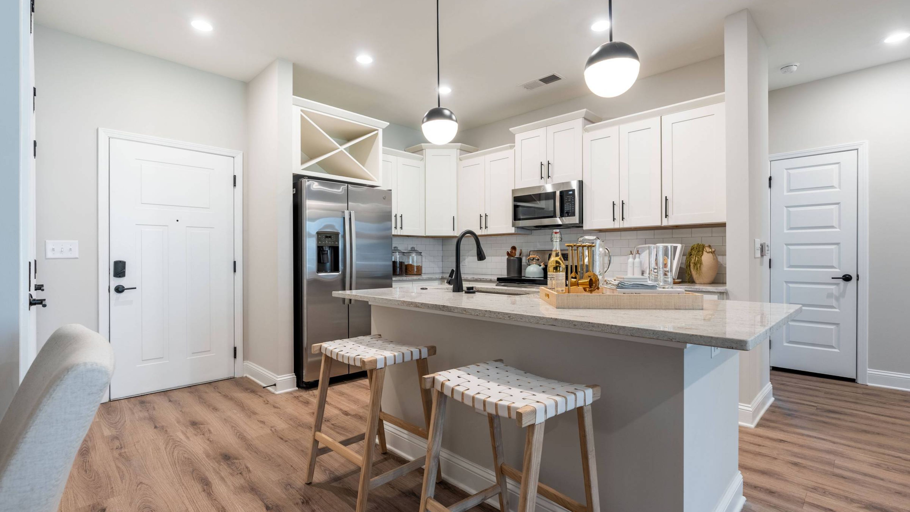 Hawthorne at Summerville apartment living space and kitchen with small dining table, kitchen peninsula, and stainless steel appliances